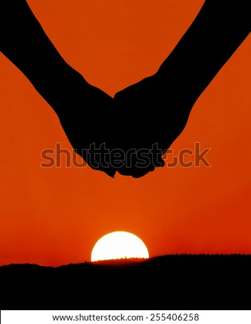lovers holding hands in front of a sunset