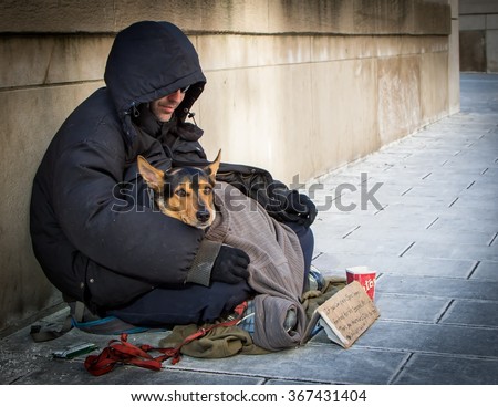 TORONTO, ONTARIO, CANADA - January 23, 2016: A homeless man and his homeless dog beg for small change outside Union Station, Toronto's main train station.
