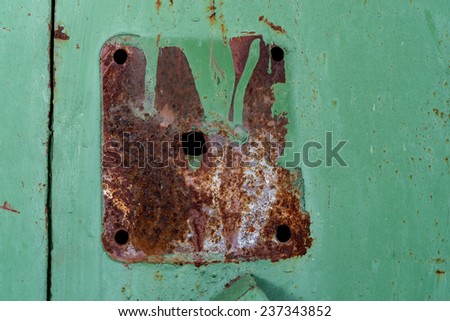 Detail of a rusted and painted over spot where a handle was attached to a metal door