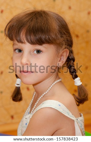 Portrait of serious six years old girl with plaits and fringe.