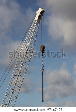 A Tall Jib Crane with Strong Metal Lifting Chains.