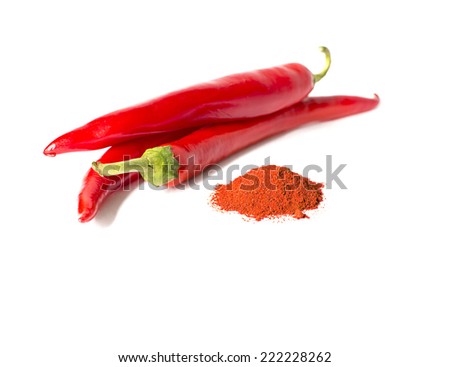 Red chili peppers next to the pepper powder pile on the white background