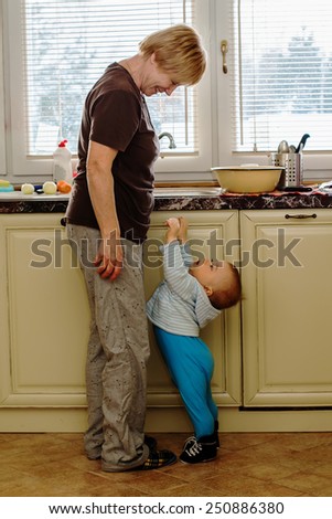 Cute child stretched out his hands to his grandmother, as though he was asking her to  pick him up in her arms