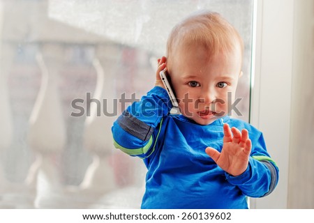 Cute baby is playing with mobile phone as he is calling to somebody