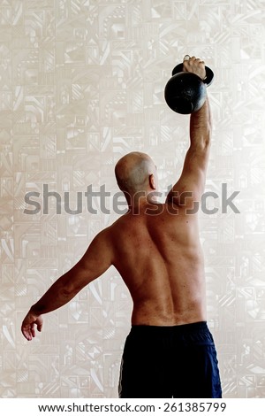 Back view of man doing workout with kettlebell background, colour, blur vertical