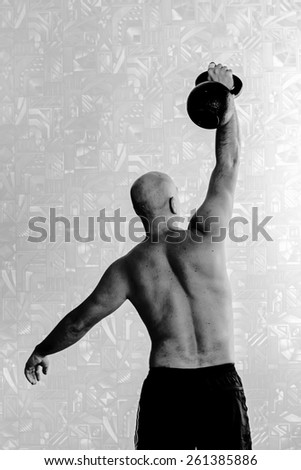 Back view of man doing workout with kettlebell background. Black-and-white, vertical
