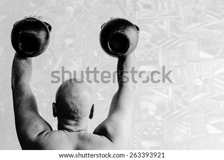 Back view of bold man lifting up two kettlebells.. Black-and-white, horizontal