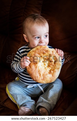 Cute baby boy biting into unleavened wheat cake (lavash)