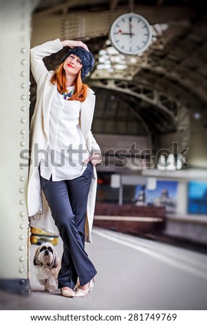 Elegant smiling ginger hair womans and hih tzu dog on the platform under the clock waiting train at the Vitebsk railway station