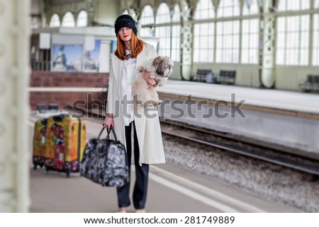 Elegant lady with shih tzu dog and suitcases on the platform waiting a train at the Vitebsk railway station in St.-Petersburg, Russia. Image with selective focus