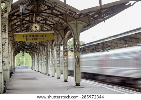 Train is arriving at platform with clock and inscription \