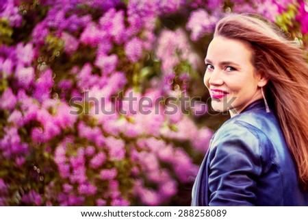 Beautiful young woman in lilac garden turning her head to look at you