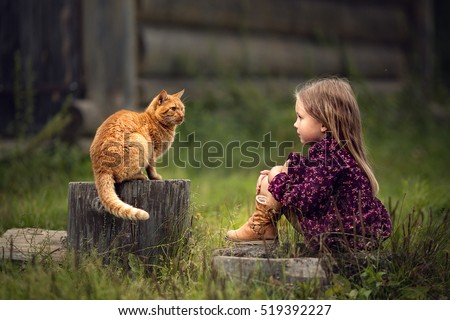 Little girl is playing with a big red cat  in the country in Russia. Image with selective focus and toning