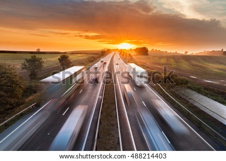 Trucks and Cars in Motion on Busy Motorway at Sunset