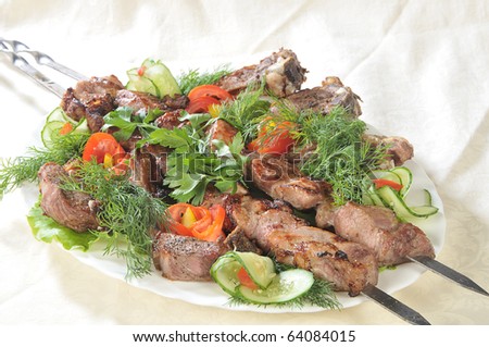 Hot dish of pieces of lamb on skewers in a dish served with vegetables.