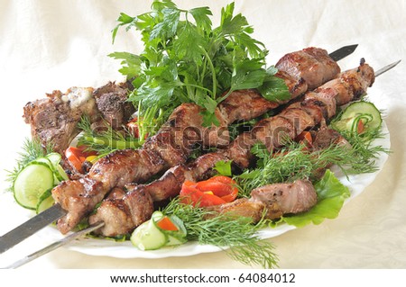 Hot dish of pieces of lamb on skewers in a dish served with vegetables.
