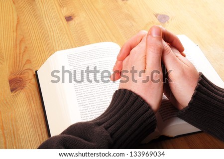 praying hand and book on desk showing religion concept praying hand and book on desk showing religion concept