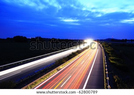 night traffic on busy highway with cars lights and blue sky