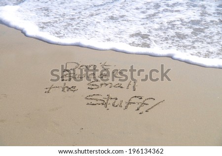Don\'t sweat the small stuff, a message written in the sand at the beach.