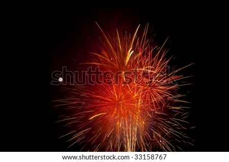 Fireworks illuminate the night sky with the moon in the background.