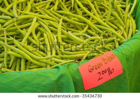 Closeup of a bin of fresh raw green beans offered for sale at a farmer's market.