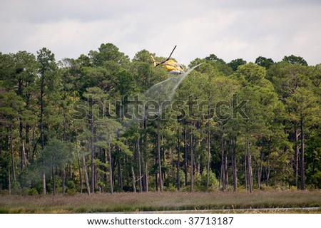 Low flying helicopter applying fertilizer to an open field.