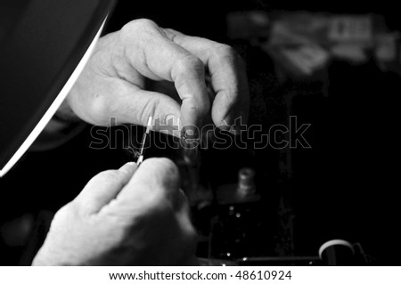 Closeup of a mans hands tying a fly lure in black and white.