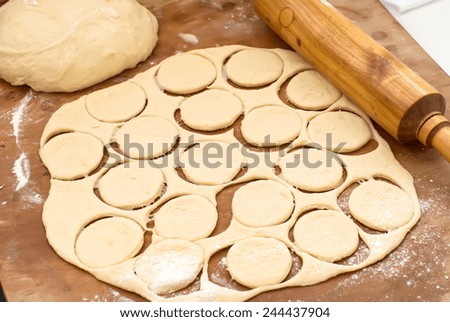 ball of raw dough, rolling pin and cut out circles from raw cookie dough rolled seam on a wooden board