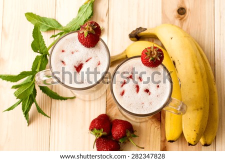 strawberry-banana milkshake in glasses and banana, and strawberry top view