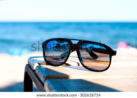 mirrored sunglasses on the table on the beach with sea views