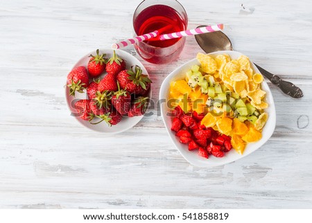 cornflakes and Rainbow  fruit salad , strawberry in plate , glass juice for  -  a healthy breakfast. The concept of proper nutrition. Top view. Copy space.