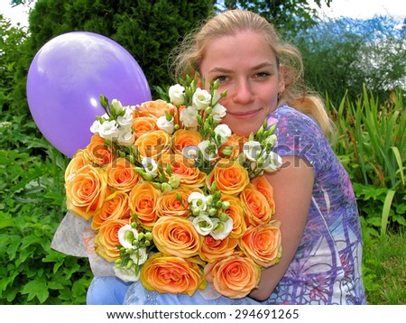 Young smiling girl with a bouquet of flowers and balloon