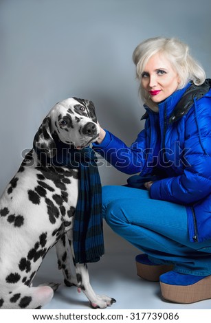 Young blonde girl sitting next to the Dalmatian dog protect
