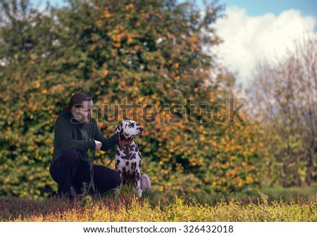 Young attractive man walking with an active dog Dalmatian on nature