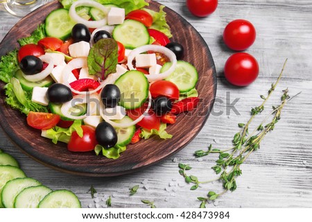 Traditional greek salad with fresh vegetables, feta cheese, black olives, and ingredients for cooking Greek salad oil, thyme, cherry tomatoes, cucumbers, salt