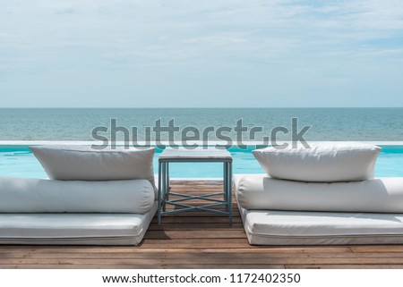 White beach bed at outdoor swimming pool seaside turquoise sea or ocean with horizon of blue sky at resort or hotel when vacation travel for relax