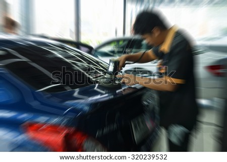 Blurred zoom of  car care staff polishing the blue car by polish machine.