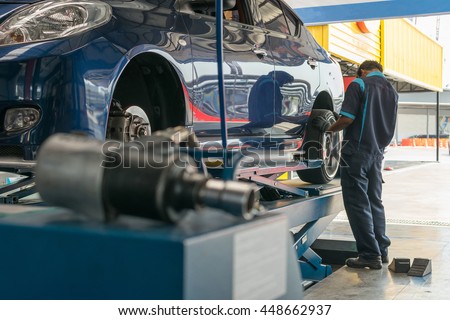 Serviceman checking suspension in a car at garage