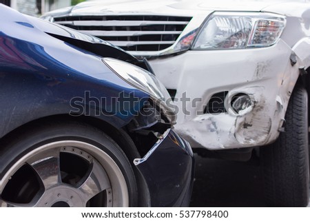 Car crash from car accident on the road in a city between saloon versus pickup wait insurance.