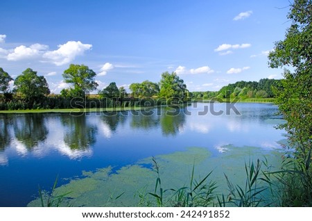 Summer landscape with low clouds. reflected on the surface of the broad river in a Sunny day