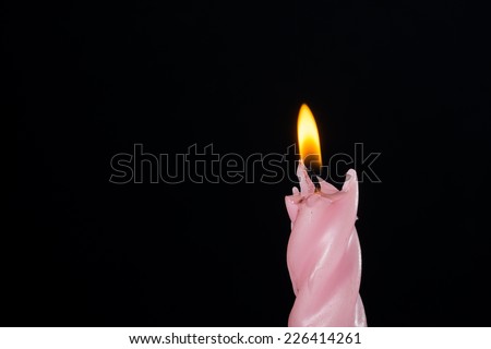 Christmas colored candle with flame on black background