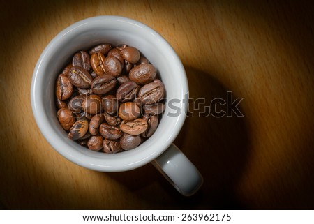 Nice cup of coffe with toasted coffee seeds inside on wood background