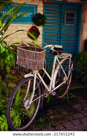 Parked bicycle with wicker basket in vintage style.