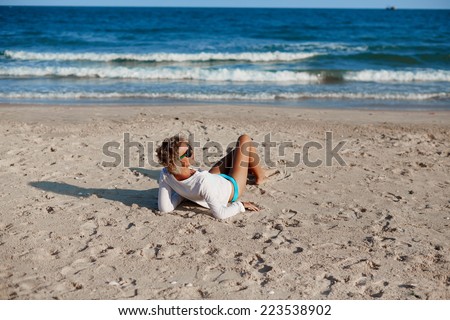 Young girl with blonde hair lying on the sand at the beach. Travel and healthy lifestyle.