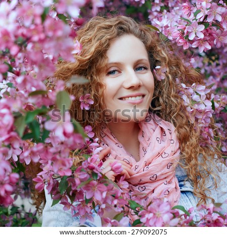 Beautiful young woman in pink sweater smiling  in peach garden. Spring in peach garden.
