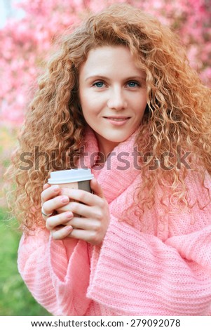 Beautiful young woman in pink sweater smiling in a pink sweater in peach garden. Spring in peach garden.