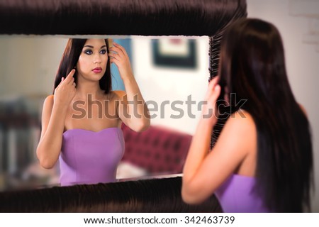 Attractive woman in evening dress fixing her hairstyle while watching at the big mirror. Selective focus