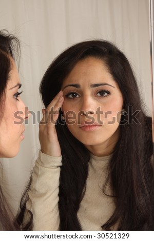 Young female at home in bathroom, looking through vanity mirror