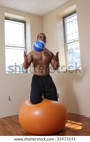Young male exercising with large and small balls