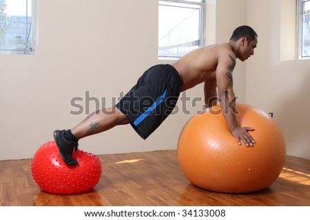 Young male exercising with large and small balls